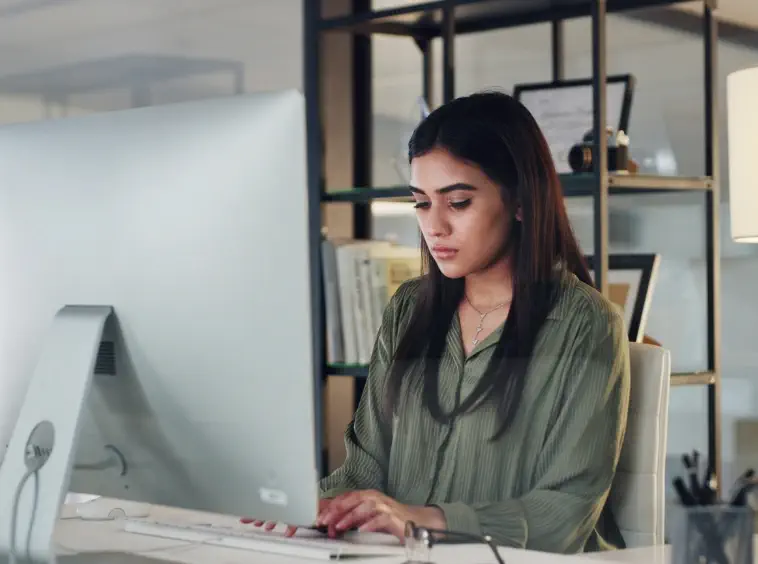 Una copywriter con camicia verde che scrive al computer un articolo su come diventare copywriter