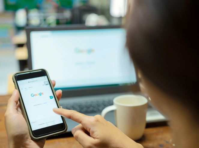 Una donna di spalle che cerca info su Google da cellulare computer, riguardo la SEO per piccoli business